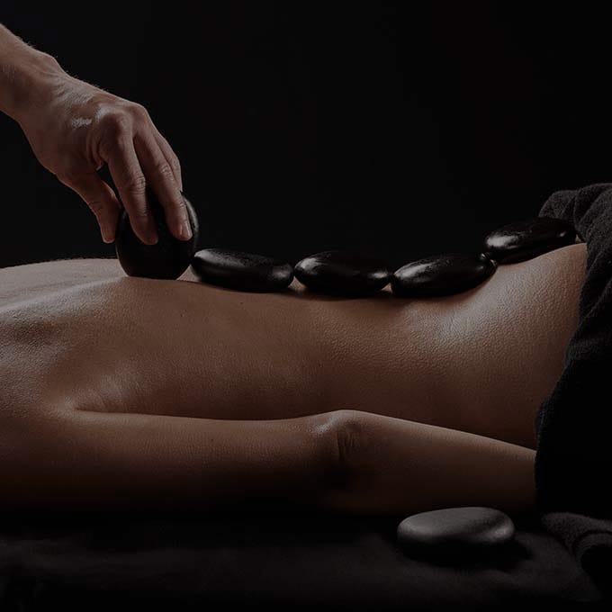 Mujer acostada boca abajo con piedras calientes en la espalda